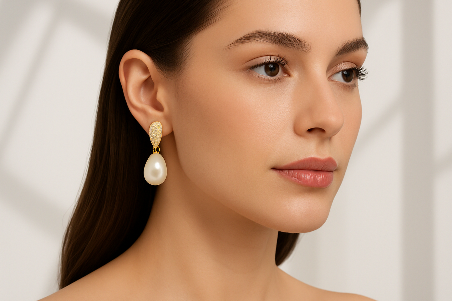 Model wearing pearl drop earrings with minimalist background
